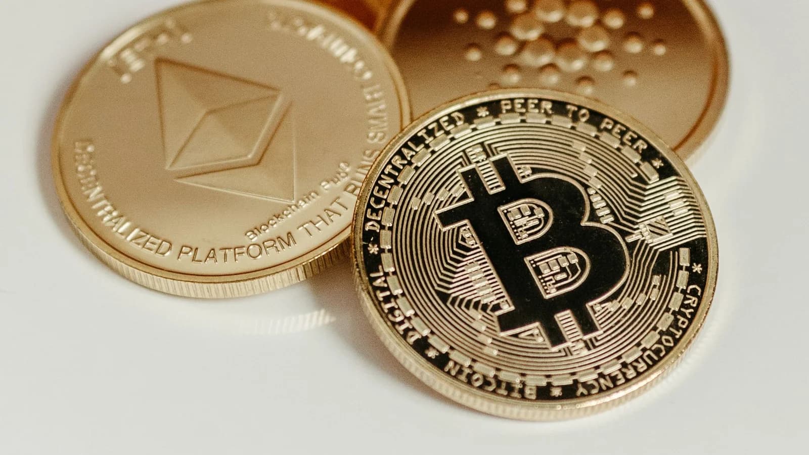 Elegant display of Bitcoin, Ethereum, and Cardano coins on a neutral background.