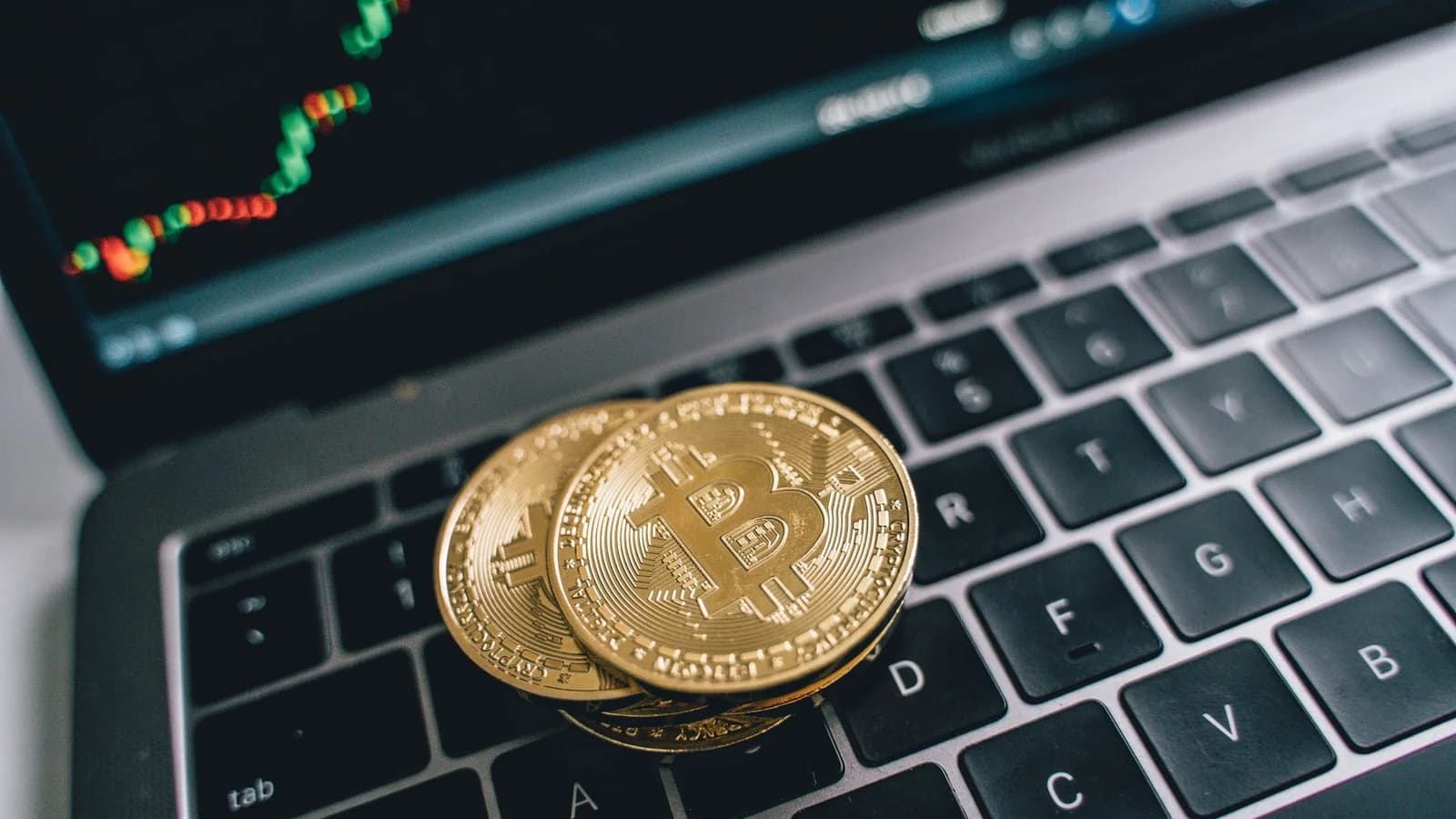 Bitcoin coins on a laptop with a market chart