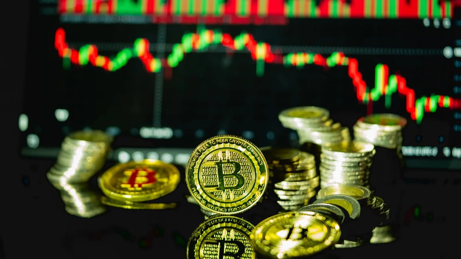 Golden bitcoins stacked in front of a fluctuating financial chart, symbolizing cryptocurrency trading.