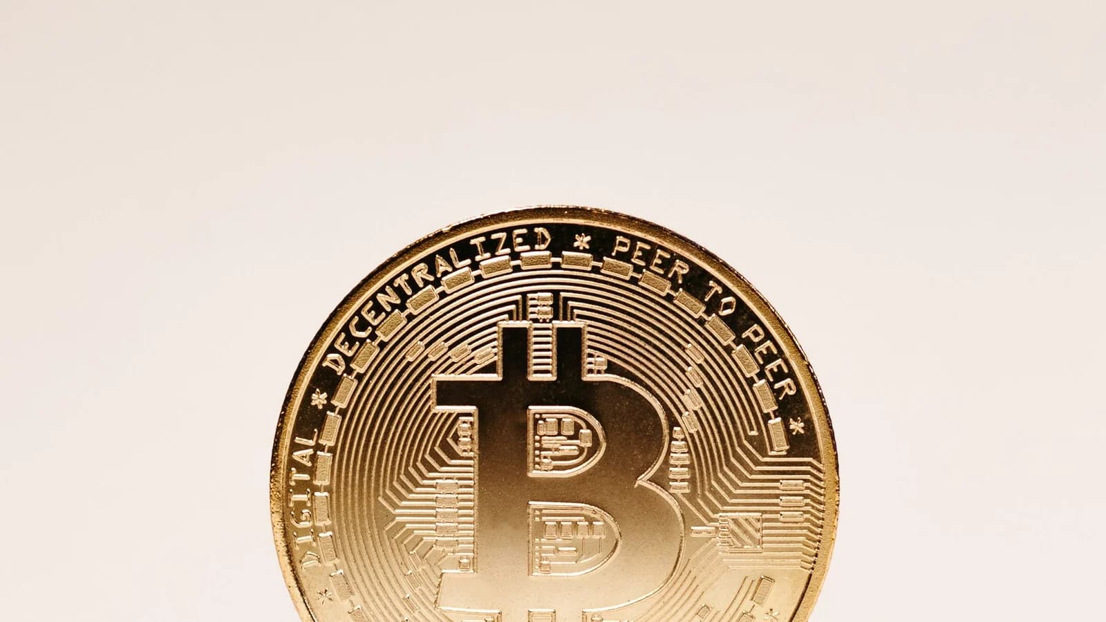 Minimalist image of a Bitcoin standing on a beige background, symbolizing cryptocurrency and wealth.