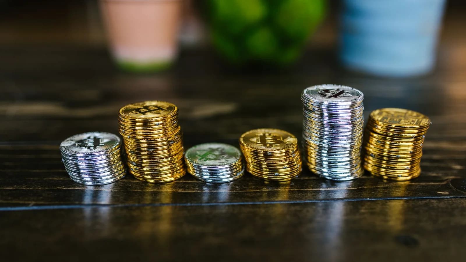 Pile of shiny gold and silver cryptocurrency coins on a wooden table.