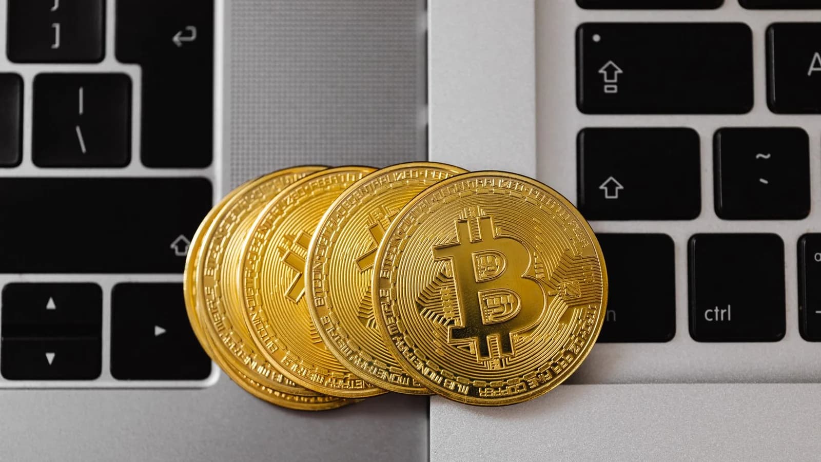 Bitcoin coins resting on laptop keyboards