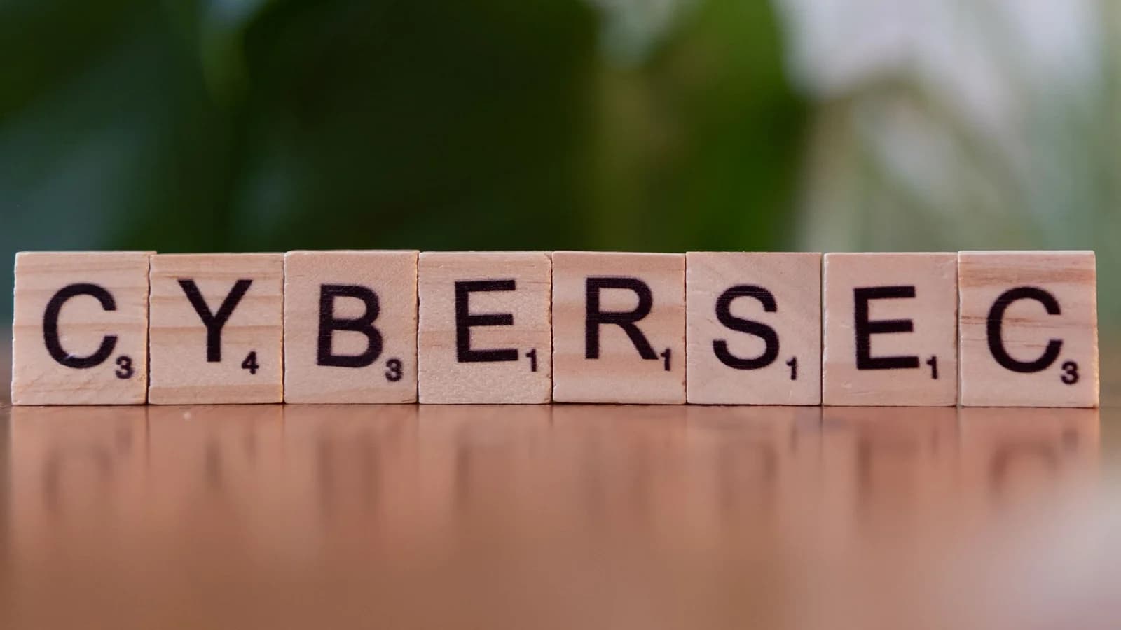 Wooden tiles spell 'CYBERSEC' against a soft-focused green background.