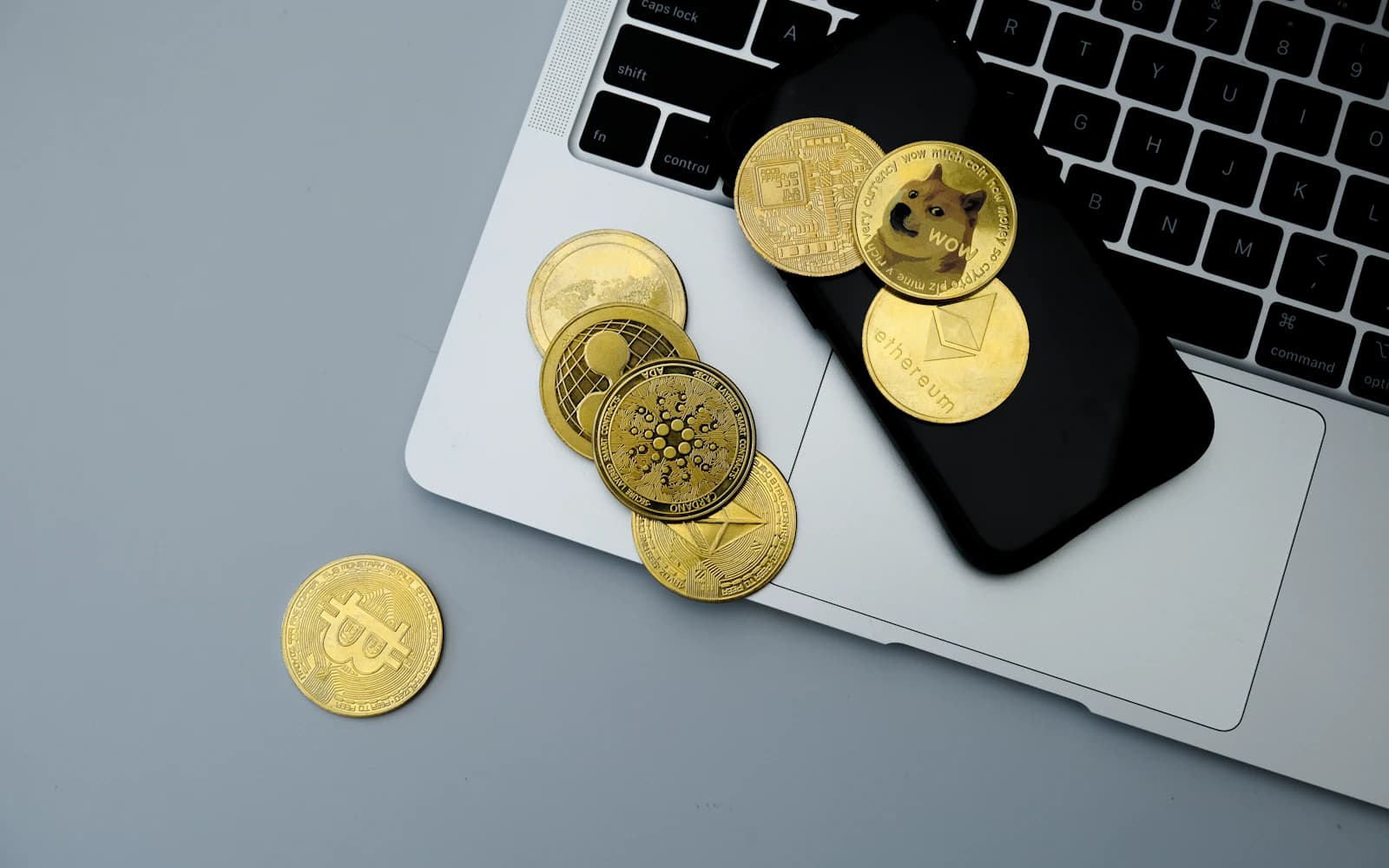 Cryptocurrency coins arranged across a laptop and smartphone. Photo: Coinhako/Unsplash.