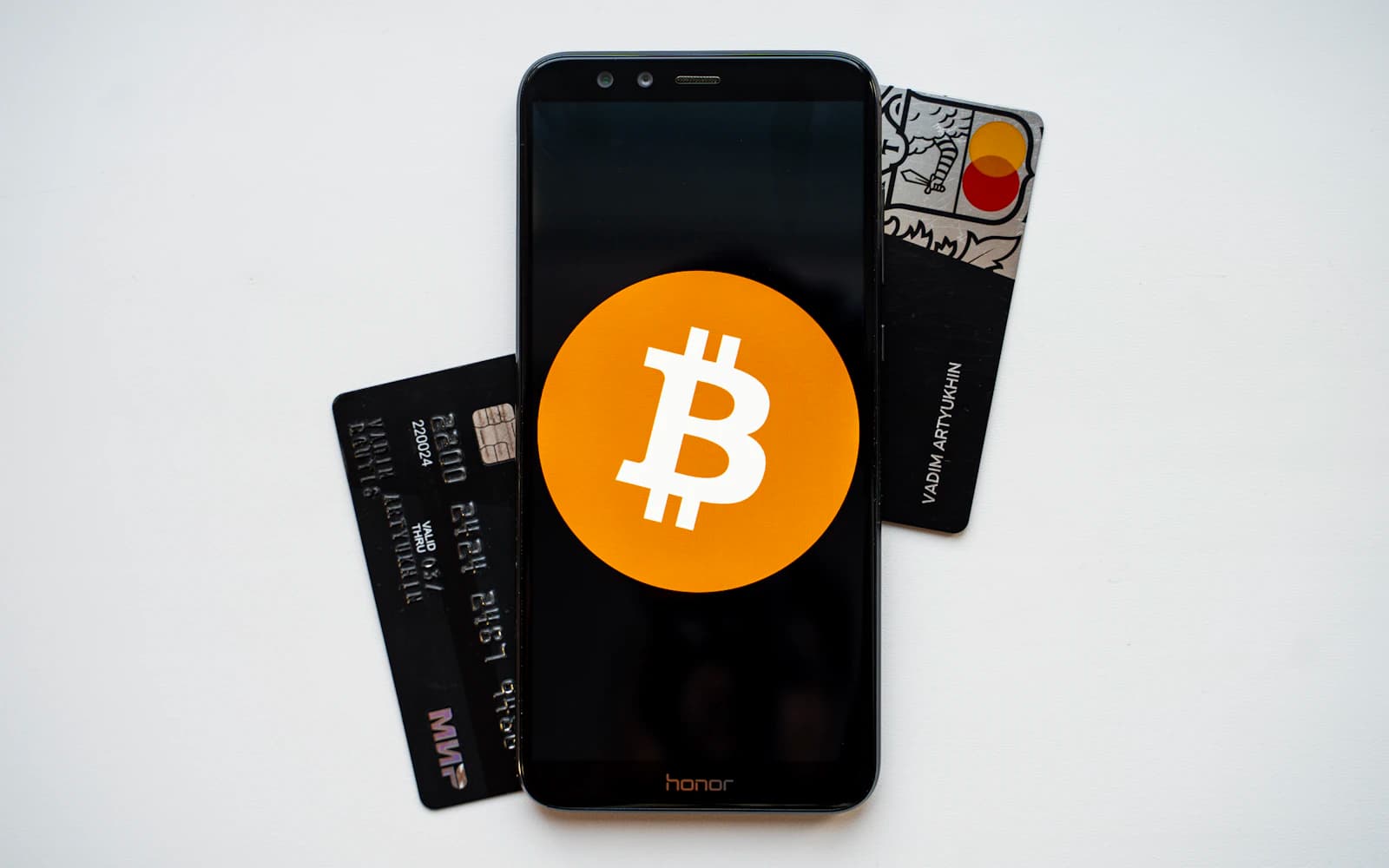 Smartphone beside payment cards illustrating a card-based crypto wallet. Photo: Unsplash.